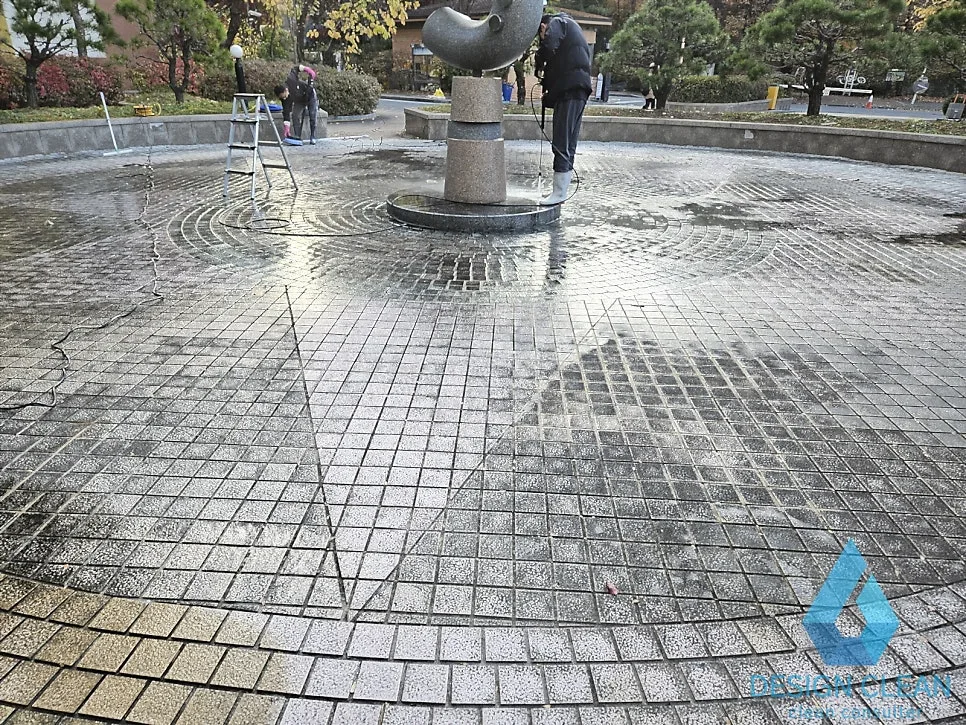 광장 바닥 고압세척 진행 중, 세척 구간과 미세척 구간 대비